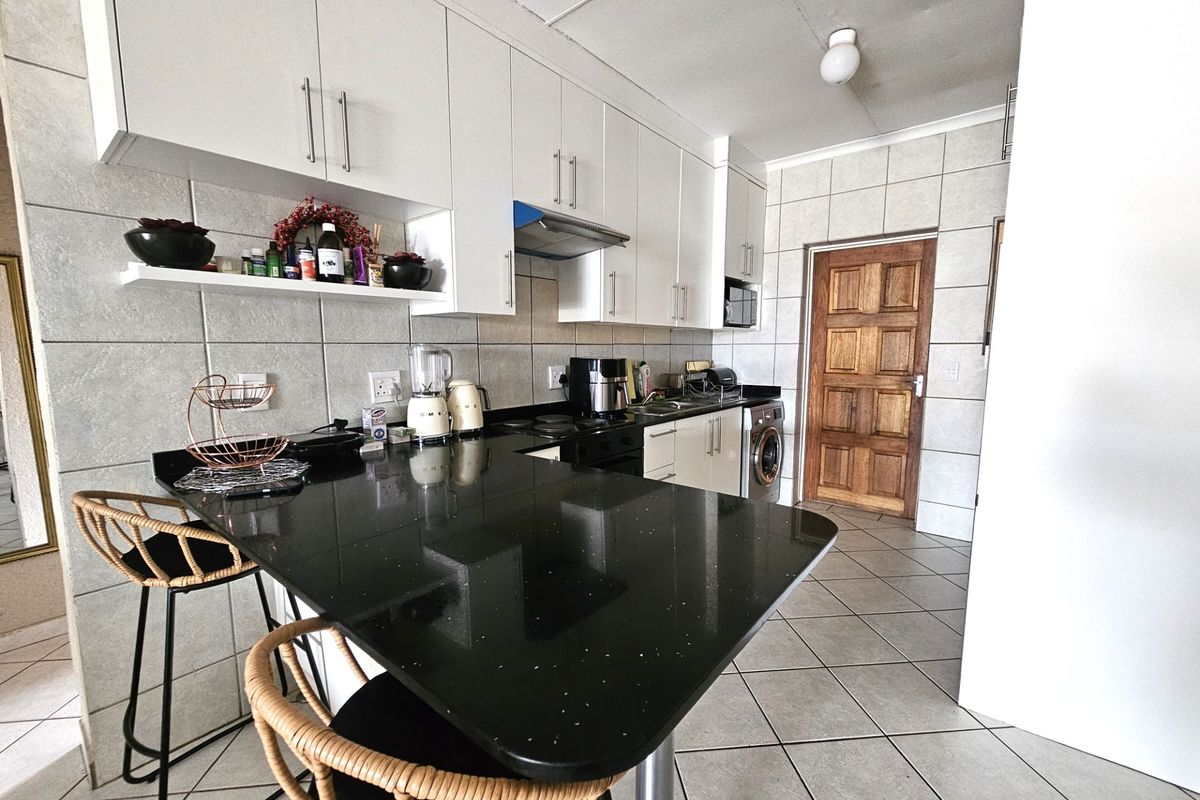 Modern kitchen featuring white cabinetry, black granite countertops, tiled backsplash, and integrated laundry appliances, offering a functional and clean workspace.
