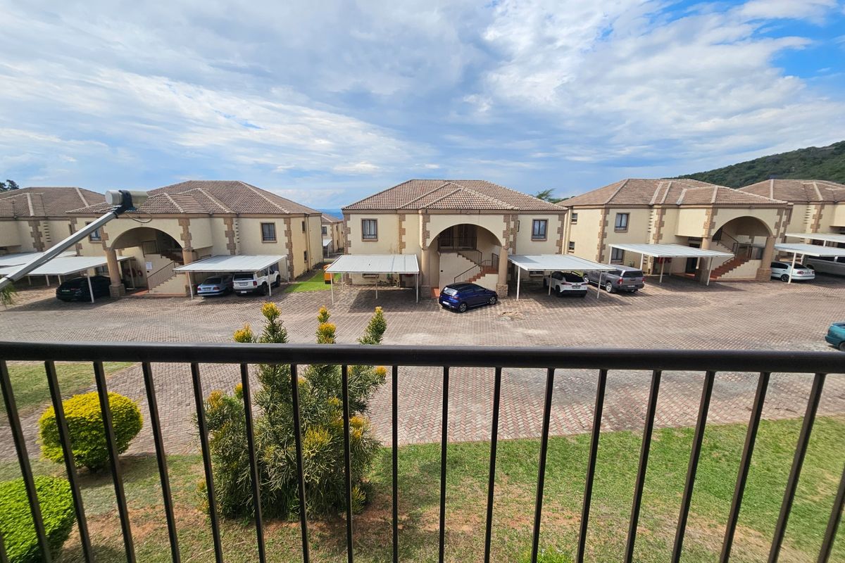 View of the apartment complex exterior featuring paved parking areas, covered carports, and well-maintained communal garden spaces.