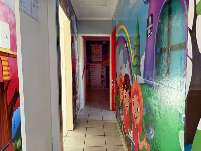 A narrow hallway featuring tiled flooring and walls currently decorated with children's themed adhesive murals.
