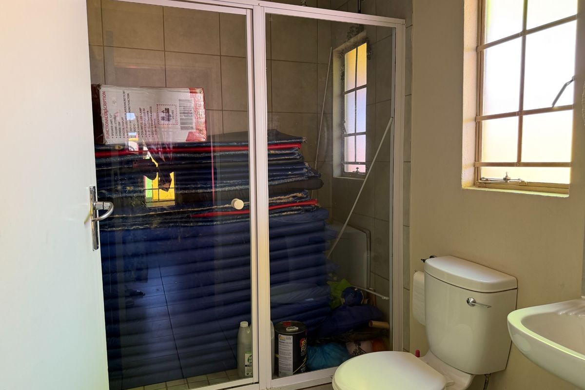 A functional bathroom featuring a shower enclosure, toilet, and washbasin, with tiled walls and a window providing natural light.