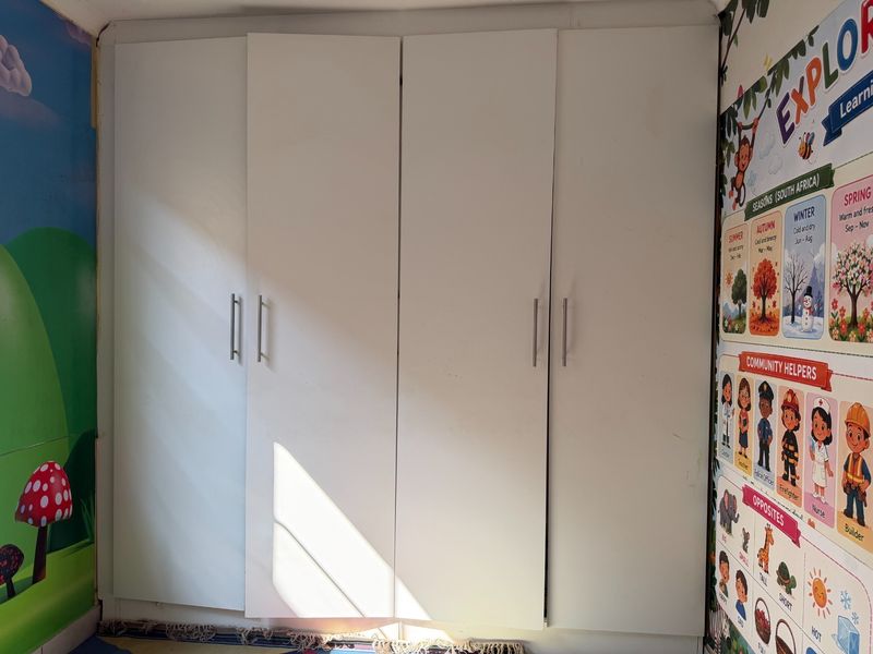A bedroom featuring white built-in cupboards with modern handles, providing ample storage space.