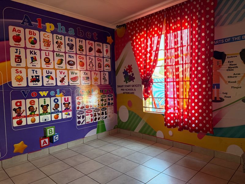 An empty room currently utilized as a classroom, featuring tiled flooring and a window with security bars.