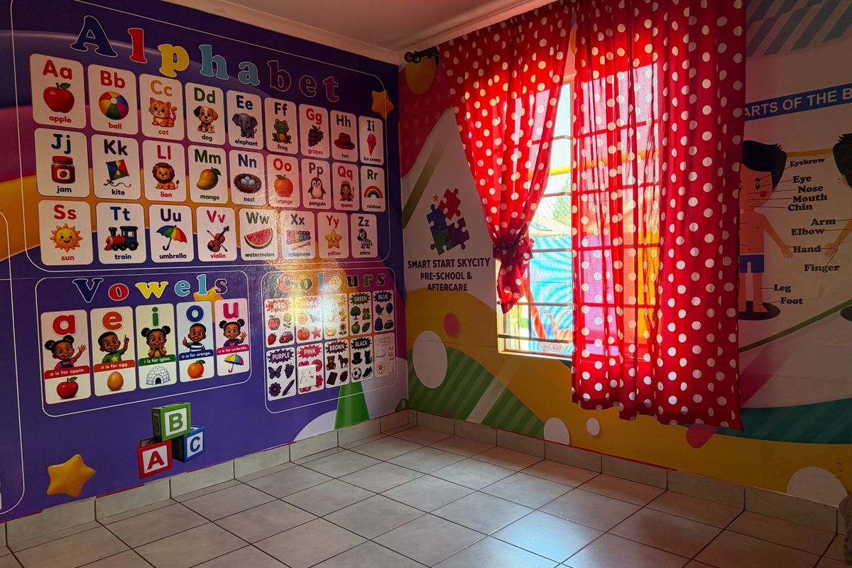 An empty room currently utilized as a classroom, featuring tiled flooring and a window with security bars.