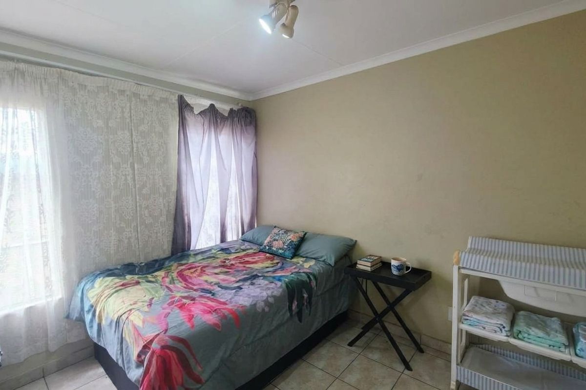 A standard bedroom featuring tiled flooring and neutral wall finishes, providing a functional space with natural light from the window.
