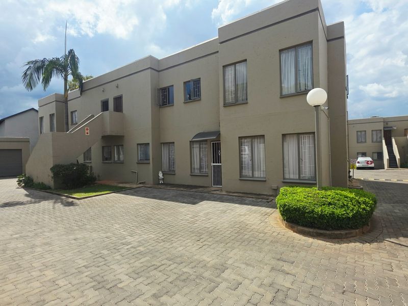 Exterior view of a multi-story townhouse complex featuring paved driveway access, external staircases, and integrated garage units.