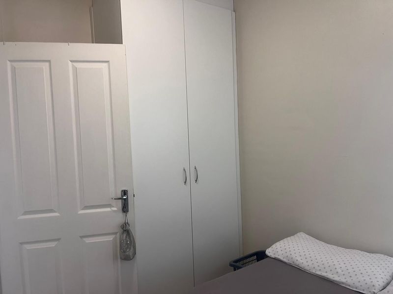 A bedroom featuring a white built-in wardrobe and a standard internal door, providing functional storage space.