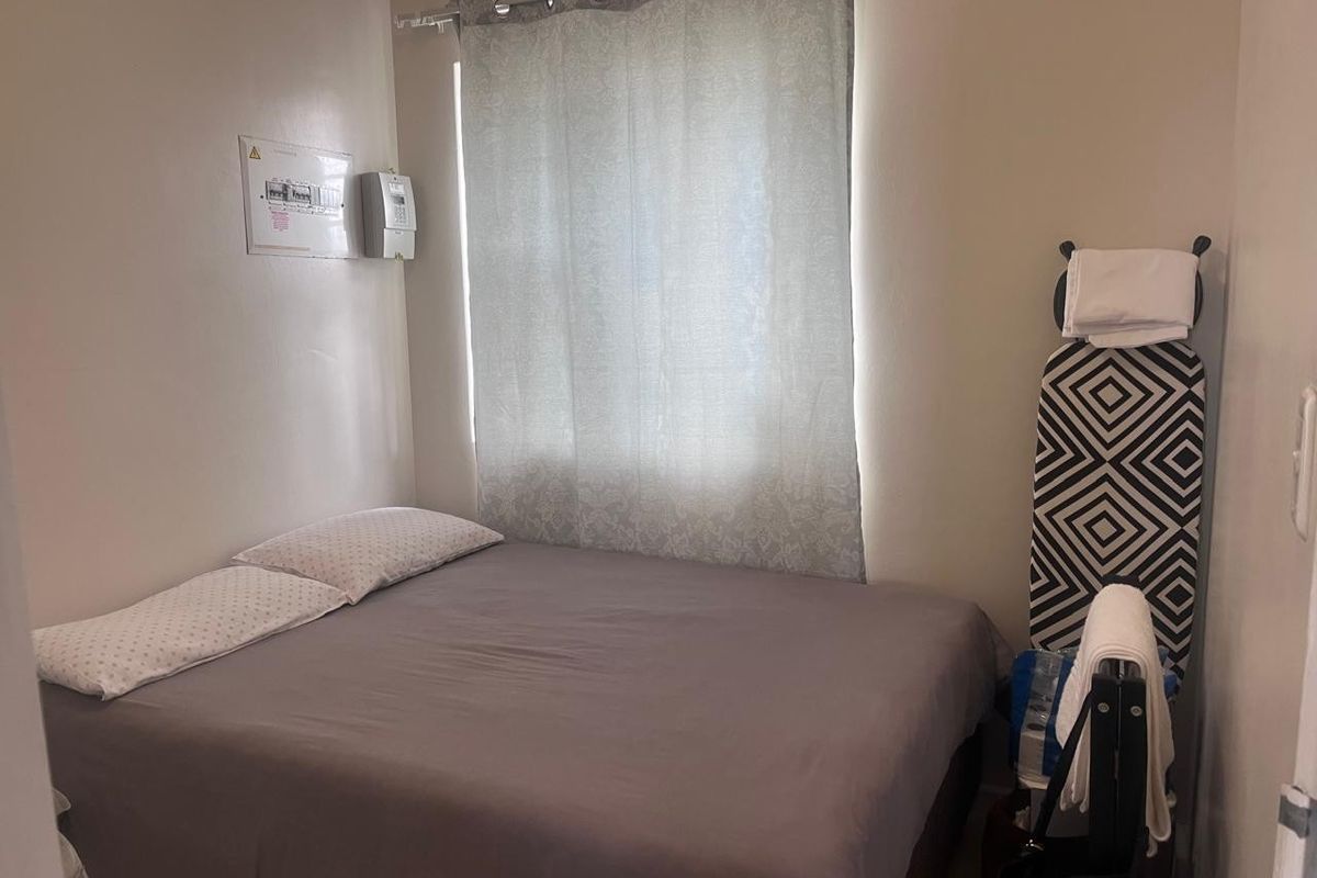 A compact bedroom featuring a wall-mounted electrical distribution board and prepaid electricity meter.