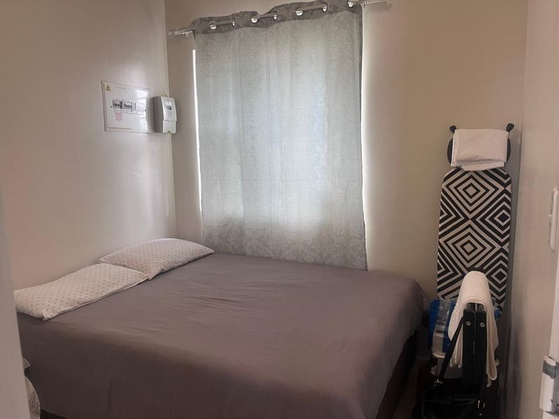 A compact bedroom featuring a wall-mounted electrical distribution board and prepaid electricity meter.