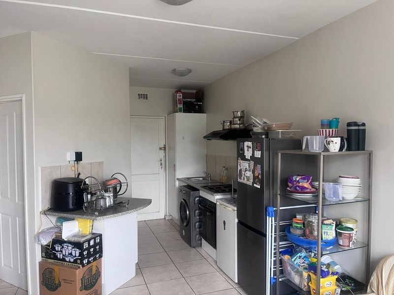 A functional kitchen featuring tiled flooring, built-in cabinetry, a hob, oven, and extractor fan, providing a practical layout for daily meal preparation.