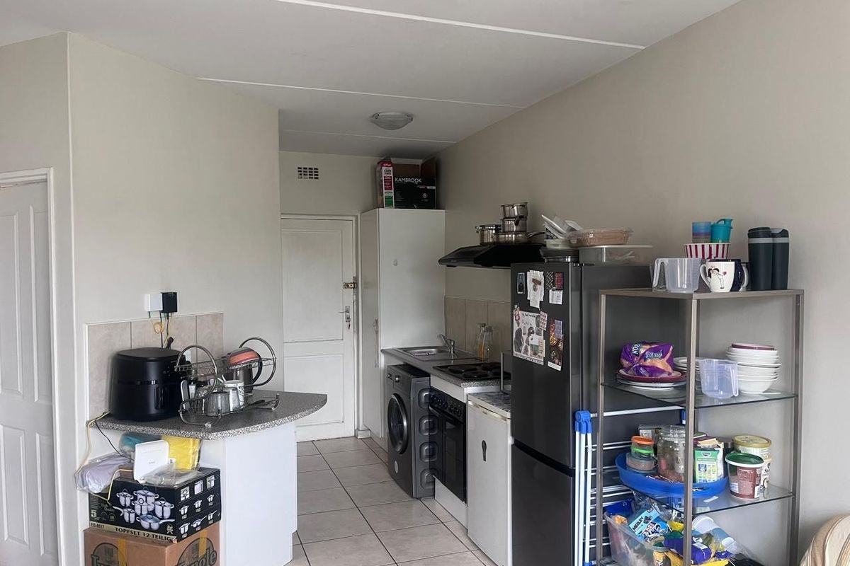 A functional kitchen featuring tiled flooring, built-in cabinetry, a hob, oven, and extractor fan, providing a practical layout for daily meal preparation.