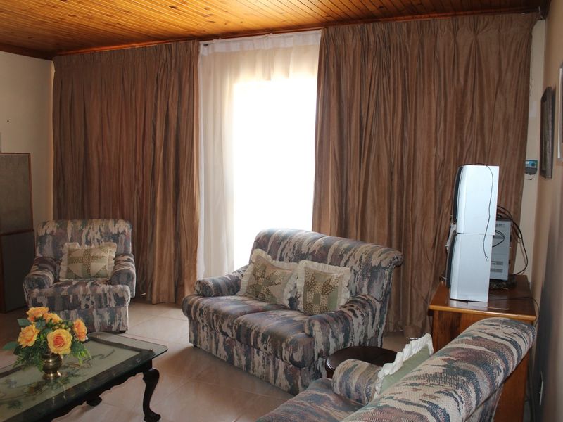 A living room featuring tiled flooring and a timber tongue and groove ceiling, with access to the outdoors via a sliding glass door.