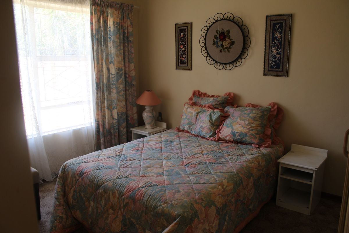 A cozy bedroom featuring carpeted flooring and a window that allows for natural light.