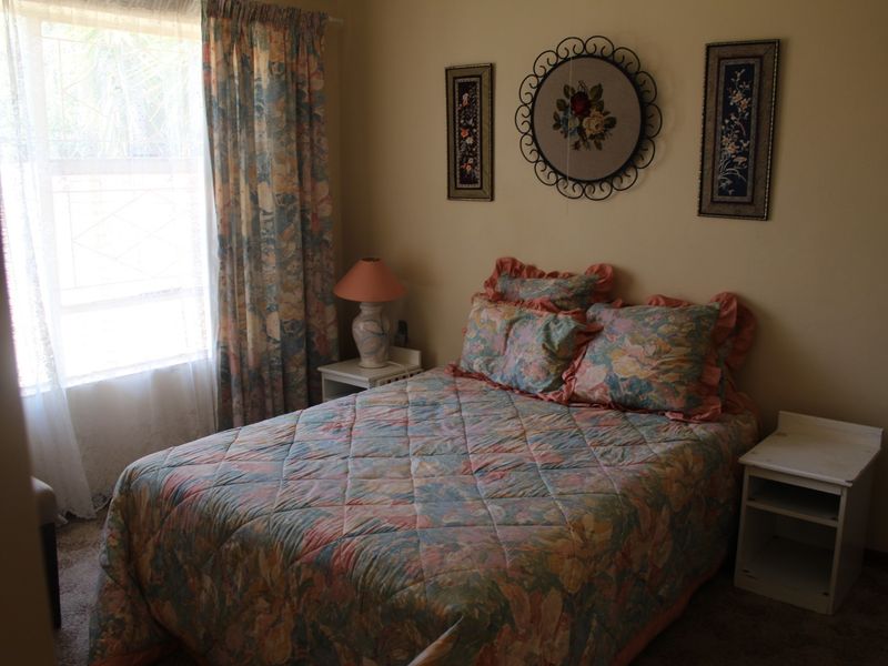 A cozy bedroom featuring carpeted flooring and a window that allows for natural light.
