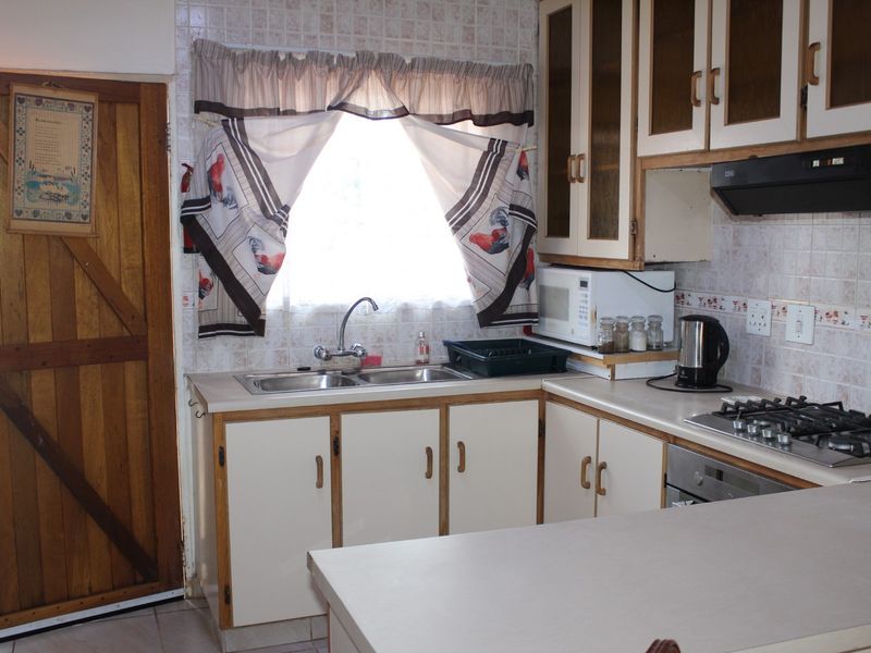 A functional kitchen featuring laminate countertops, built-in cabinetry, a gas hob, and a double bowl sink with a tiled splashback.