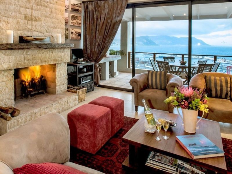 Spacious living room featuring a prominent stone fireplace and large sliding glass doors that open onto a balcony with scenic coastal views.