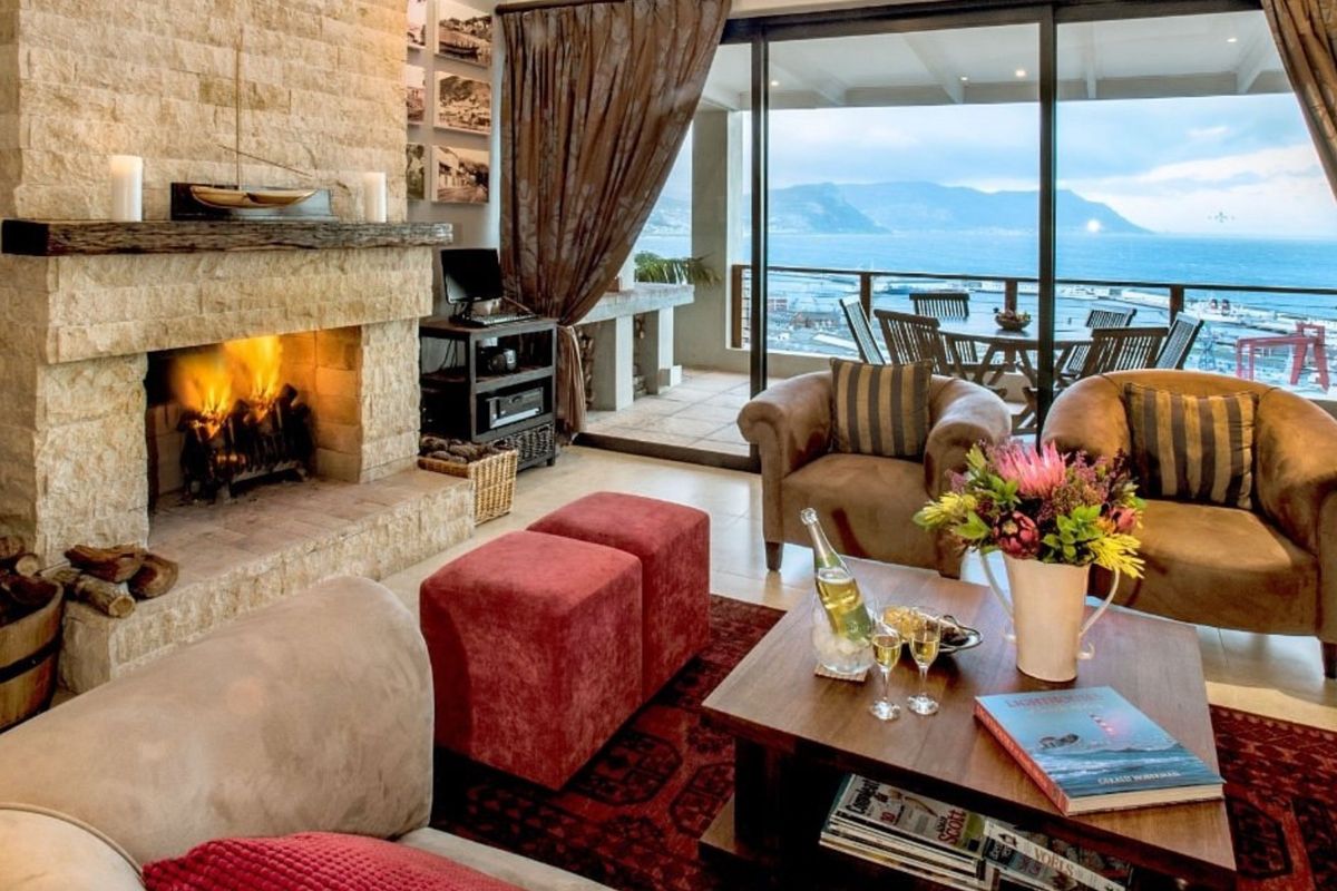 Spacious living room featuring a prominent stone fireplace and large sliding glass doors that open onto a balcony with scenic coastal views.