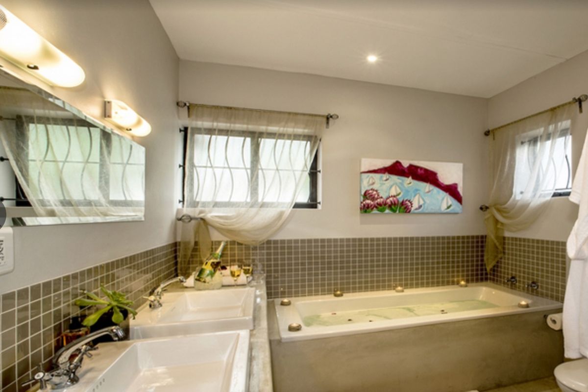 A well-appointed bathroom featuring a double vanity with modern basins, a built-in bathtub, and neutral tiled splashbacks.