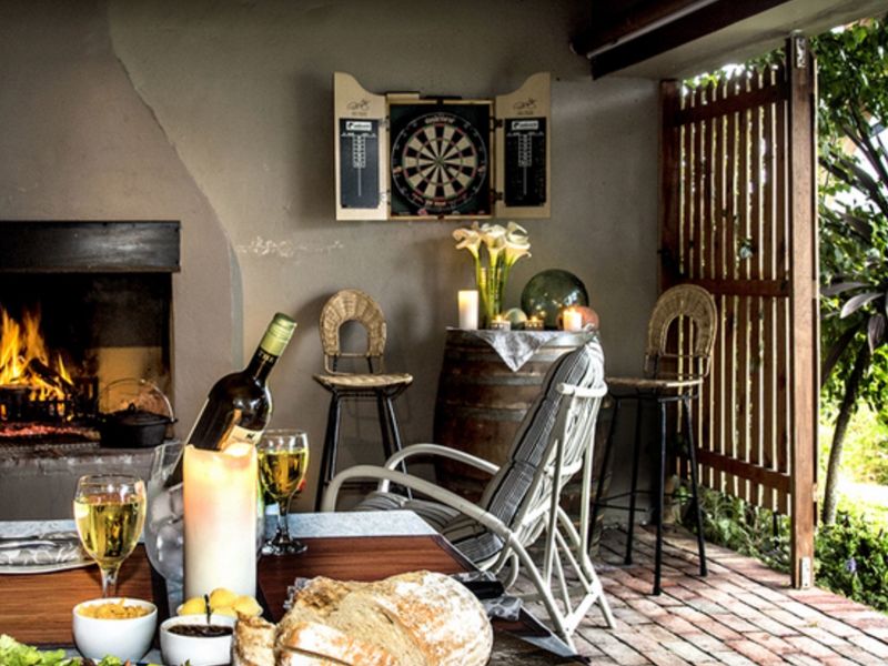 Covered outdoor patio featuring a built-in fireplace, brick flooring, and a timber privacy screen, creating a cozy entertainment space.