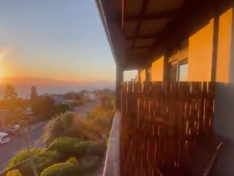 An elevated balcony area featuring a sunset view over the surrounding neighborhood and landscape.