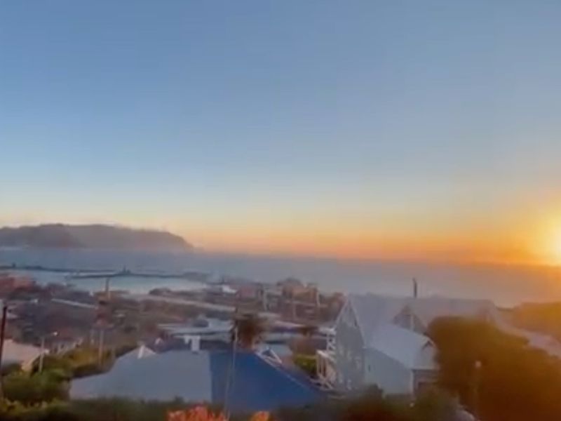 A scenic coastal view overlooking the harbor and surrounding landscape at sunset.