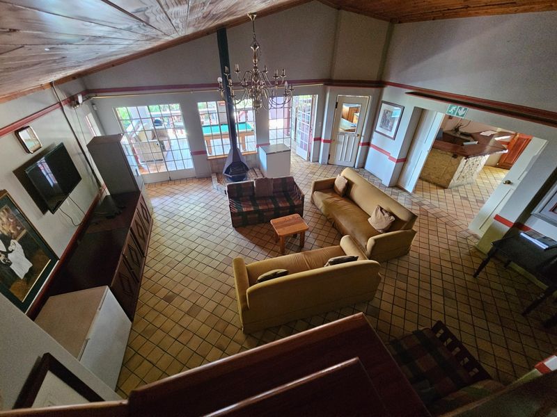 Spacious living room featuring a vaulted timber ceiling, tiled flooring, a central freestanding fireplace, and direct access to the outdoor patio area.