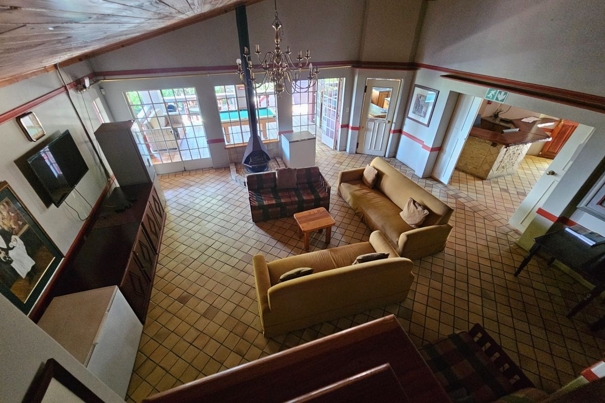 Spacious living room featuring a vaulted timber ceiling, tiled flooring, a central freestanding fireplace, and direct access to the outdoor patio area.
