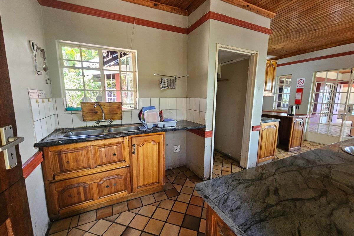 A functional kitchen featuring wooden cabinetry, granite countertops, a double basin sink, and a distinctive wooden ceiling with tiled flooring.