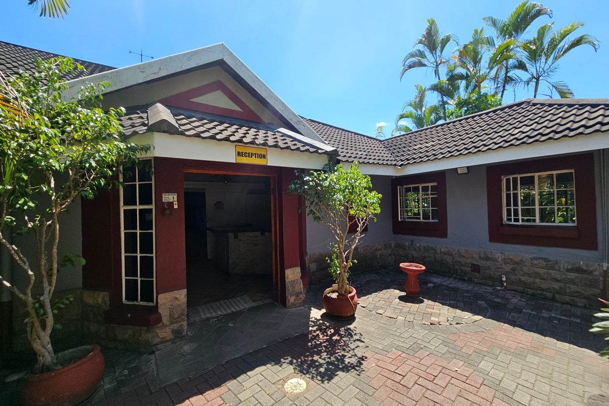 Front entrance area featuring a paved courtyard, stone cladding, and a reception doorway with a tiled roof structure.