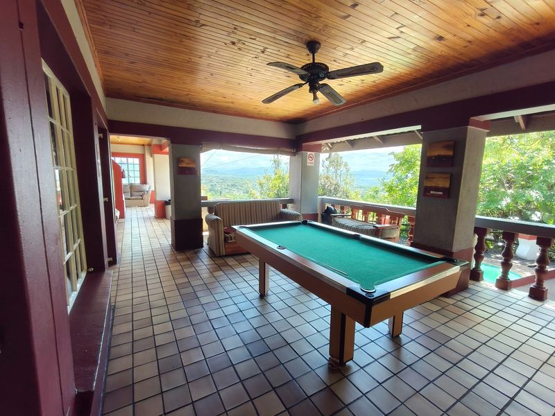Spacious covered patio featuring a timber-clad ceiling, ceiling fan, and tiled flooring, offering an open-air entertainment space with scenic views.