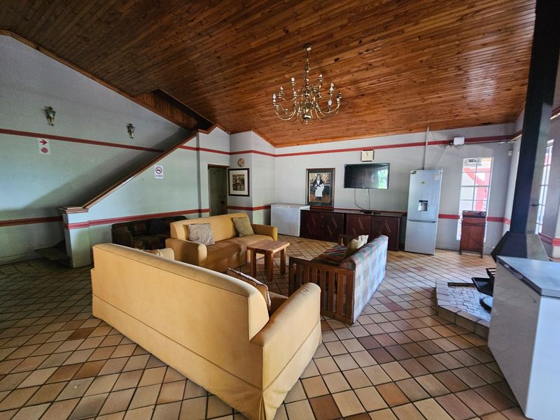 Spacious living area featuring a high timber-clad ceiling, ceramic tiled floors, and a built-in fireplace, offering a rustic and open layout.