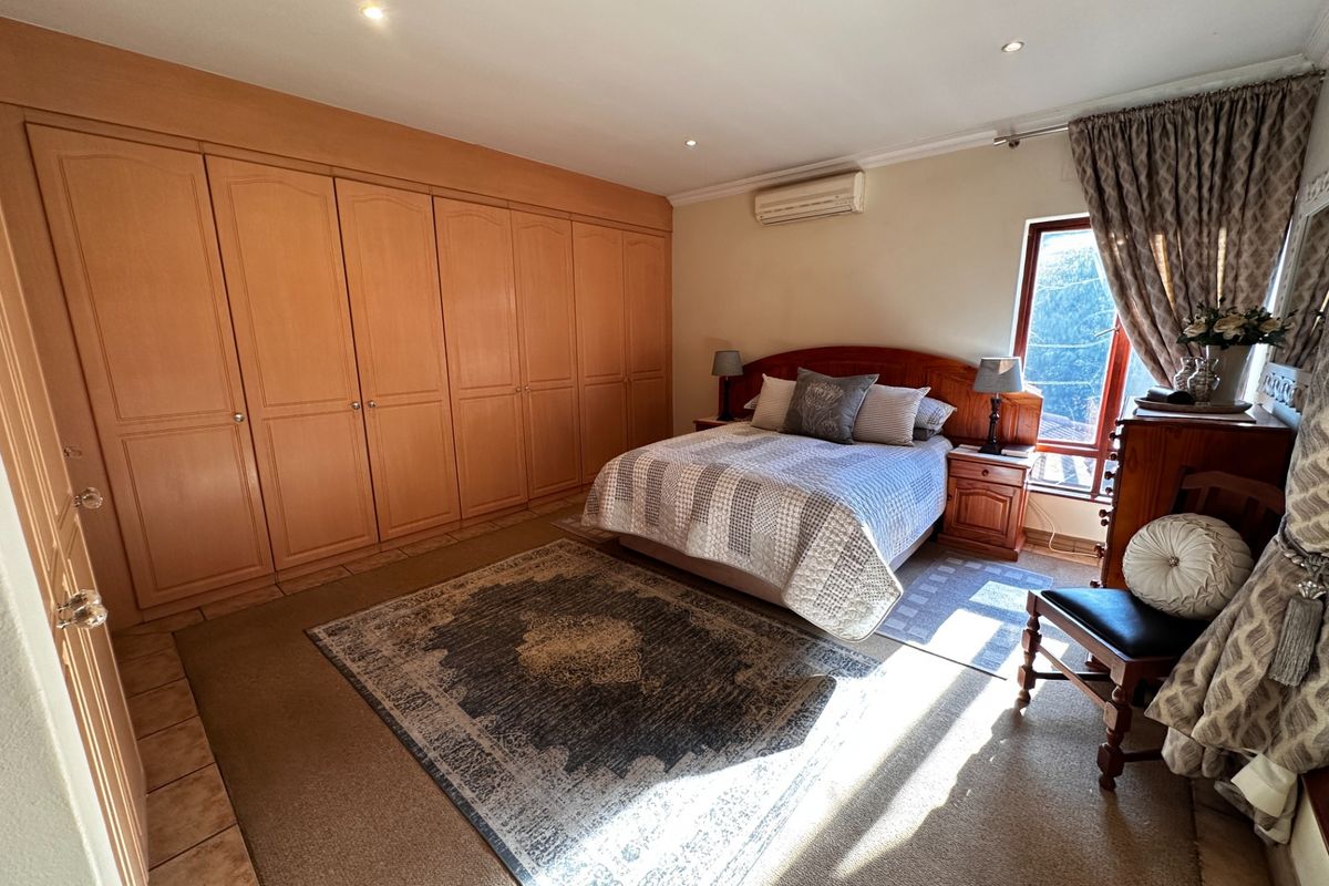 Spacious bedroom featuring extensive built-in wooden cabinetry, tiled flooring, and a wall-mounted air conditioning unit.