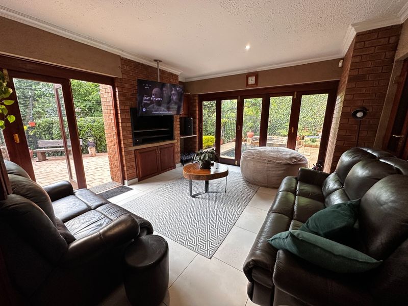 Spacious living room featuring exposed brick walls, tiled flooring, and large wooden folding doors that provide seamless access to the outdoor patio area.