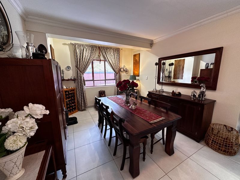 A well-maintained dining room featuring tiled flooring, coved ceilings, and a window with fitted blinds, providing a comfortable space for formal dining.