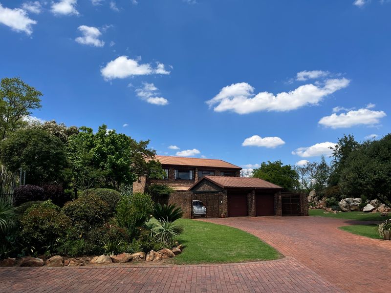 Front elevation of a double-story brick townhouse featuring a tiled roof, double garage, and a well-maintained paved driveway and garden.