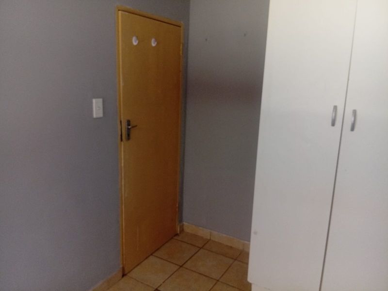 A simple bedroom featuring tiled flooring, a built-in wardrobe, and a standard internal door.