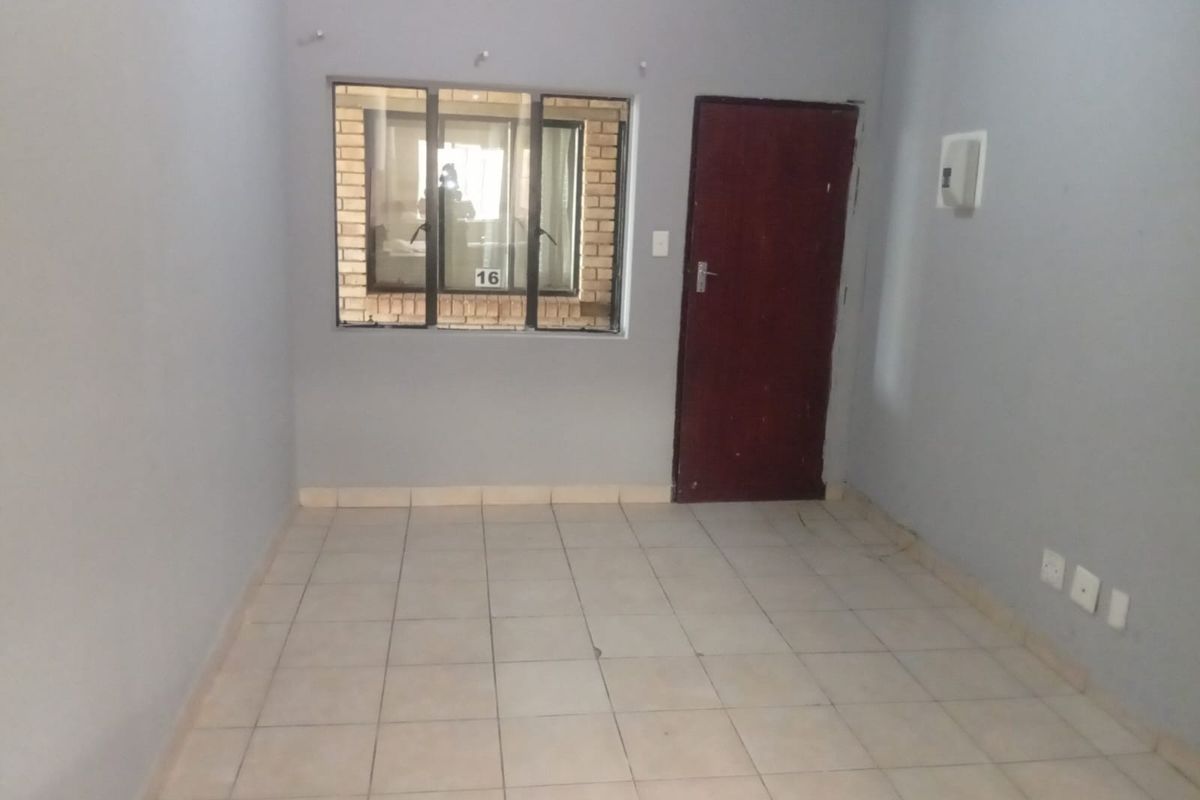 An empty living room featuring tiled flooring, a timber door, and an aluminium window, providing a blank canvas for interior design.