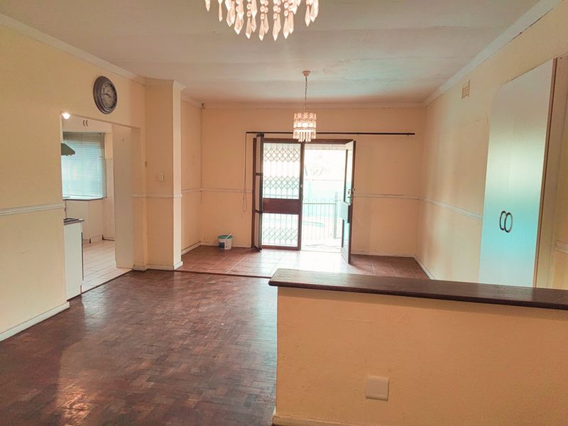 Spacious open-plan living area featuring parquet and tiled flooring, built-in cabinetry, and direct access to the exterior through a security gate.
