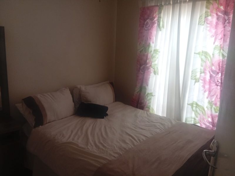 A standard bedroom featuring a window with floral curtains, providing natural light to the space.