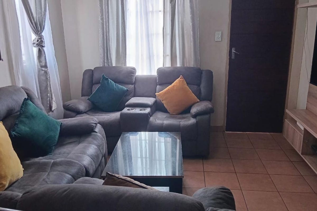 A comfortable living room featuring tiled flooring and a built-in media unit, providing a functional space for relaxation and entertainment.