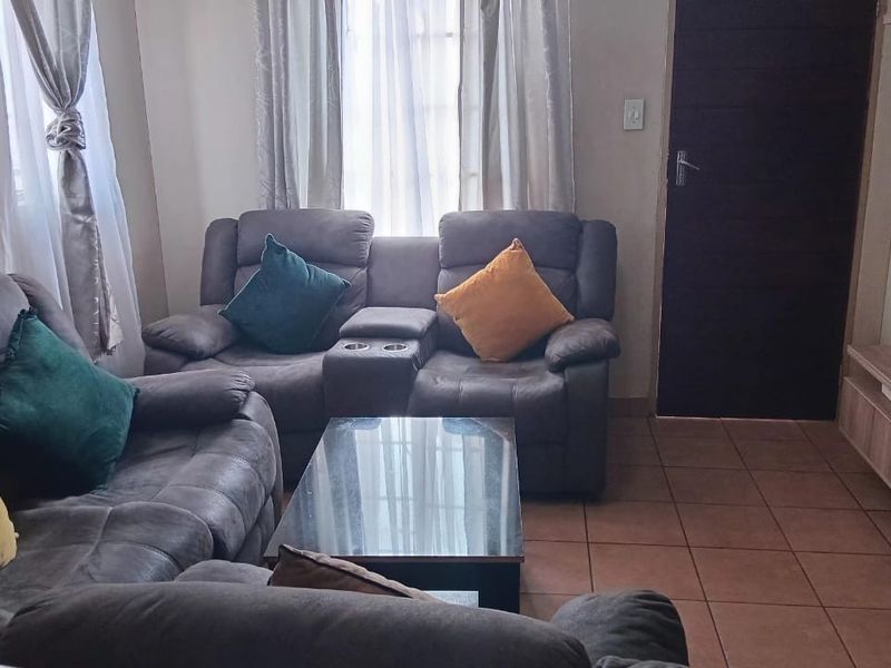 A comfortable living room featuring tiled flooring and a built-in media unit, providing a functional space for relaxation and entertainment.