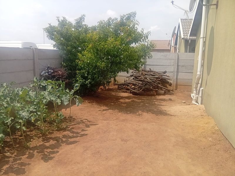 Rear yard area featuring a precast concrete boundary wall and unpaved ground, offering potential for landscaping or outdoor development.