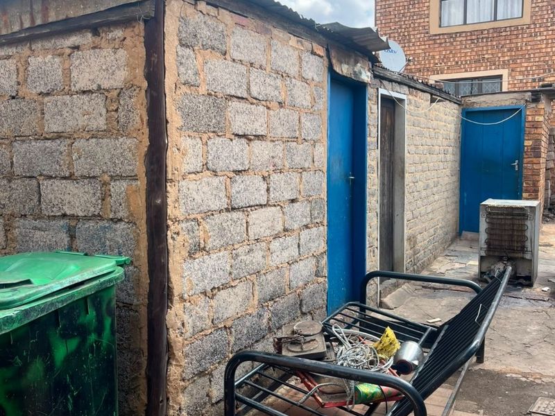 Rear exterior view of the property showing a utility structure with concrete block walls and paved outdoor area.