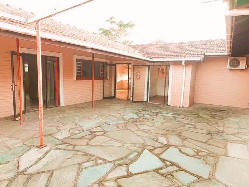 Spacious outdoor patio area featuring flagstone paving, covered roof structure, and multiple access points to the interior living spaces.