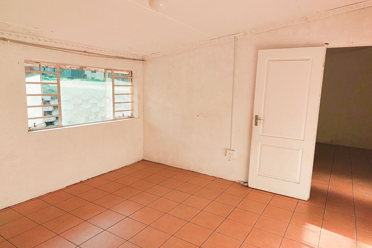 An empty bedroom featuring tiled flooring, a metal-framed window, and a standard internal door, presenting a blank canvas for renovation or interior design.