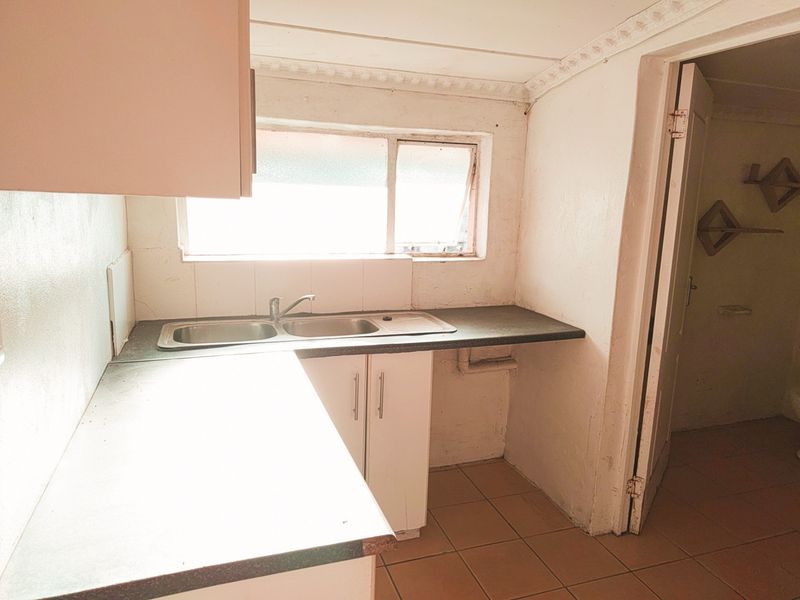 A dated kitchen featuring a double sink, laminate countertops, and base cabinetry, requiring cosmetic updates to improve its overall condition and appeal.