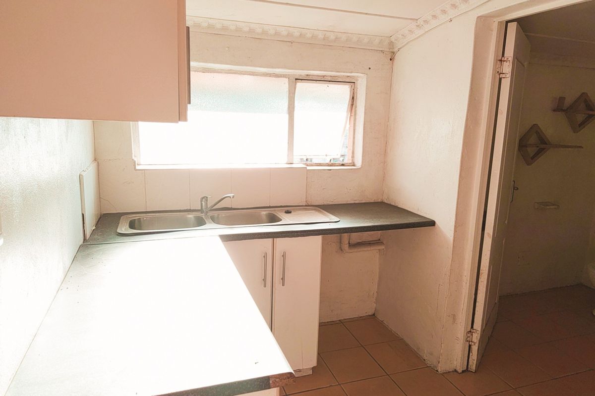 A dated kitchen featuring a double sink, laminate countertops, and base cabinetry, requiring cosmetic updates to improve its overall condition and appeal.