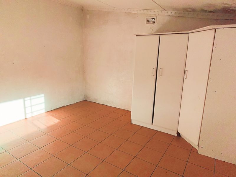 A vacant bedroom featuring tiled flooring and a built-in wardrobe, requiring cosmetic updates to the walls to improve its overall condition.