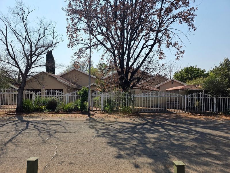 Front elevation of a residential property featuring a tiled roof, secure metal perimeter fencing, and a gated driveway entrance.