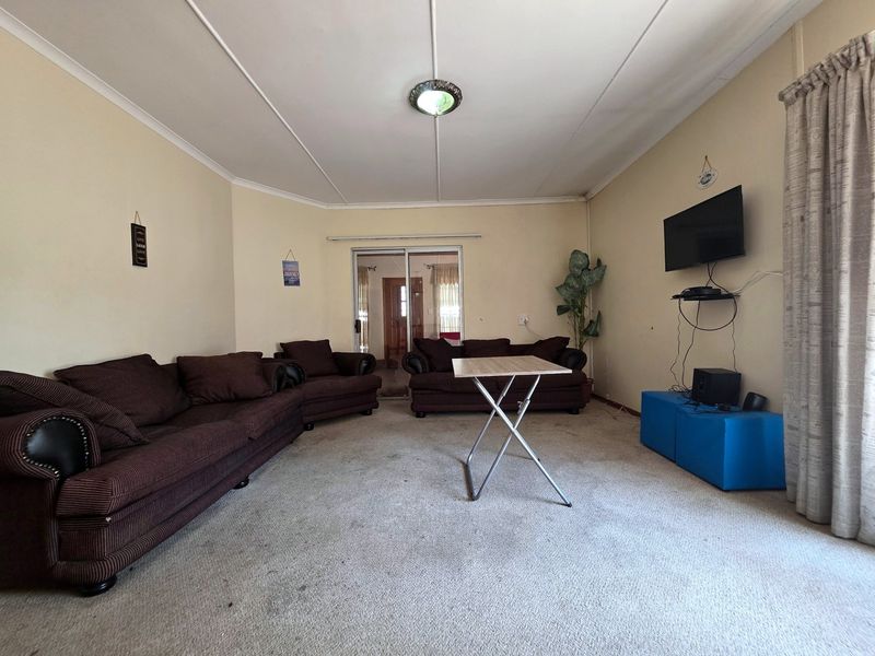 A spacious living room featuring carpeted flooring, a sliding glass door providing natural light, and neutral wall finishes.