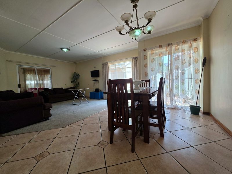 Spacious open-plan living and dining area featuring a mix of tiled and carpeted flooring with direct access to the outdoor patio through sliding doors.